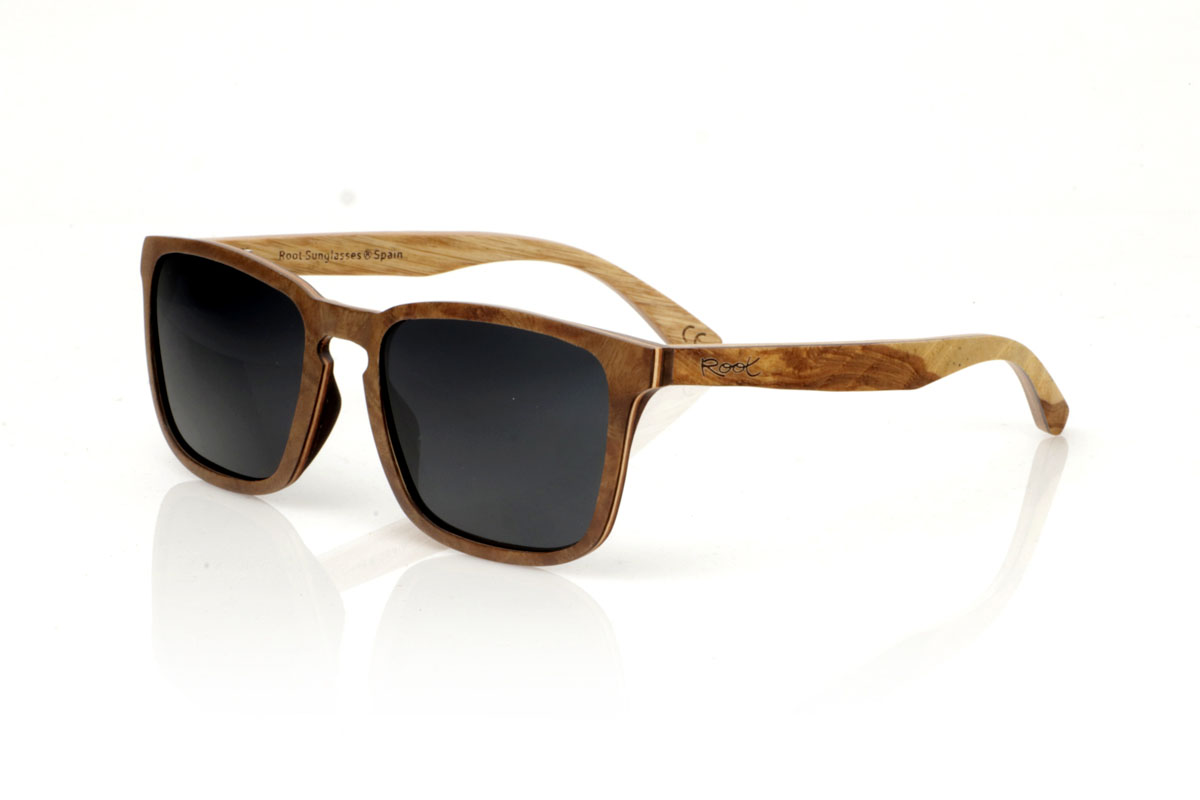 Wood eyewear of Burr OLIVER. OLIVER wooden sunglasses, medium in size and with a square shape with rounded and soft lines, are the perfect balance between design and nature. Made with a careful lamination of olive wood on the outside and interspersed with layers of beech wood, they stand out for the warm color and unique grain that olive wood offers. This combination not only provides exceptional resistance, but also makes each pair a unique piece. With a measurement of 145x47 and a caliber of 53, the OLIVER adapts wonderfully, offering comfort and unmistakable style to those who wear them. Ideal for those looking to stand out with an accessory that speaks of elegance and commitment to the environment. for Wholesale & Retail | Root Sunglasses® 